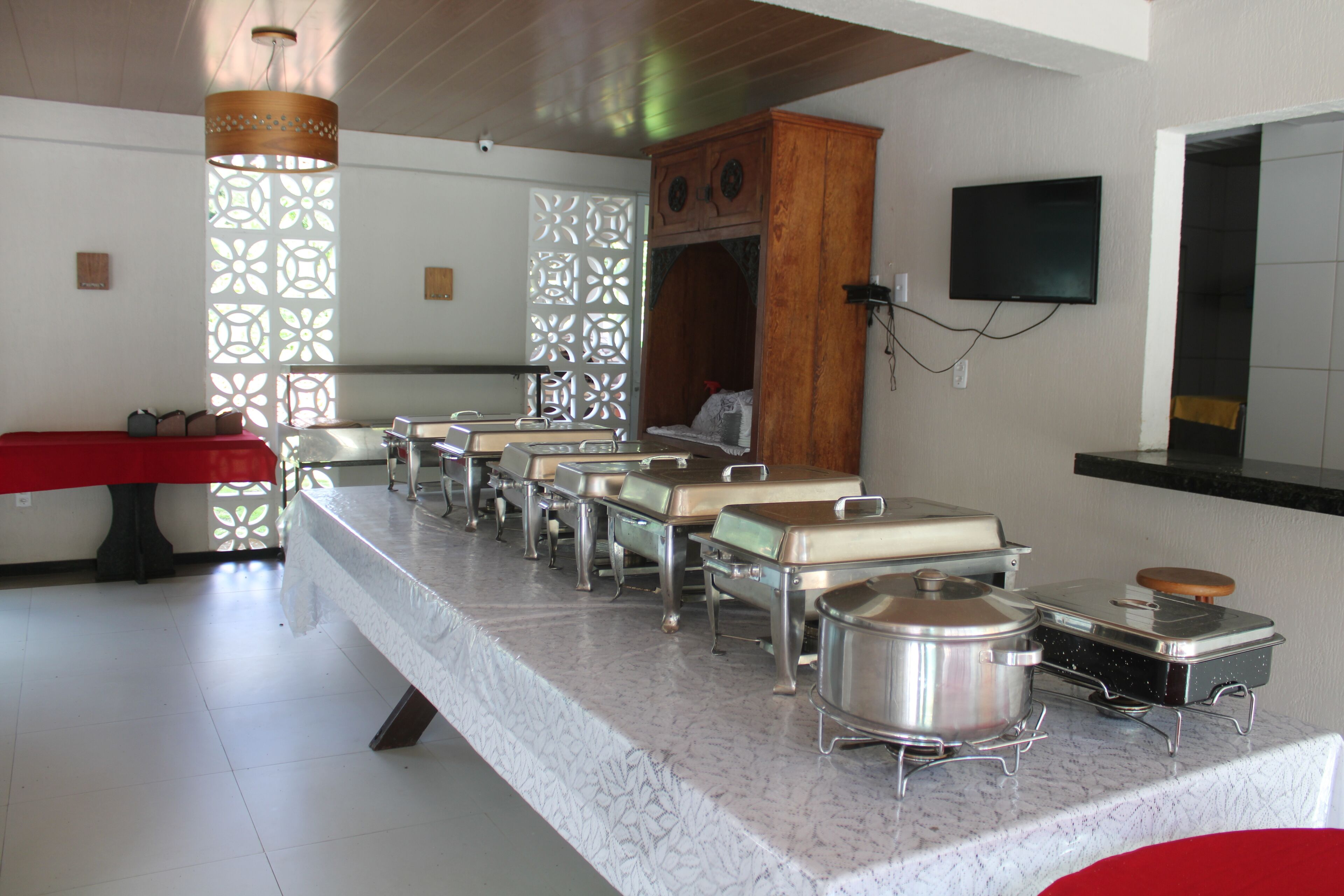 A buffet setup with multiple serving stations and a television mounted on the wall.