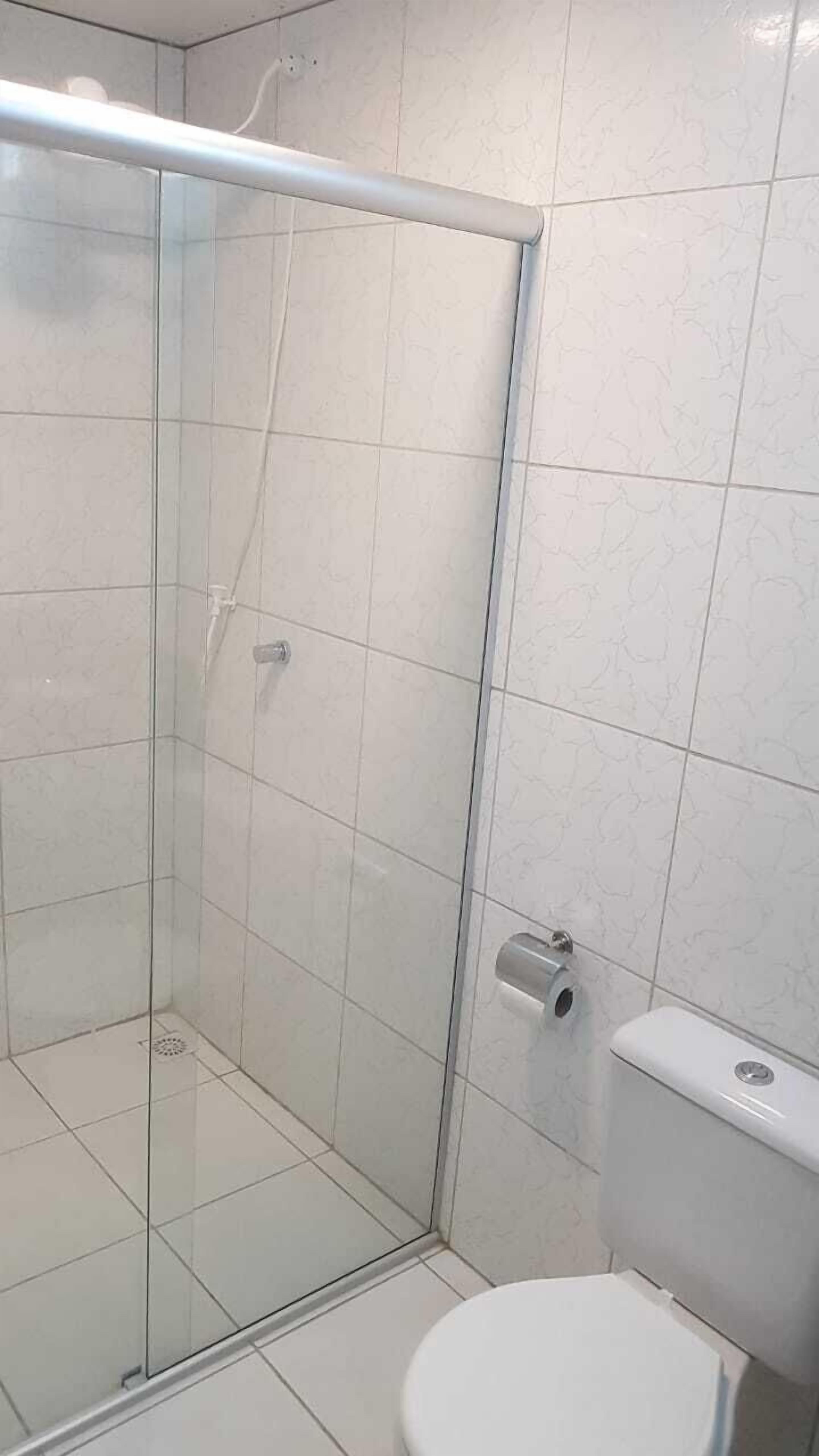 Una ducha con puerta de cristal, un inodoro y paredes de azulejos.