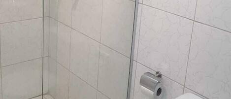 Una ducha con puerta de cristal, un inodoro y paredes de azulejos.