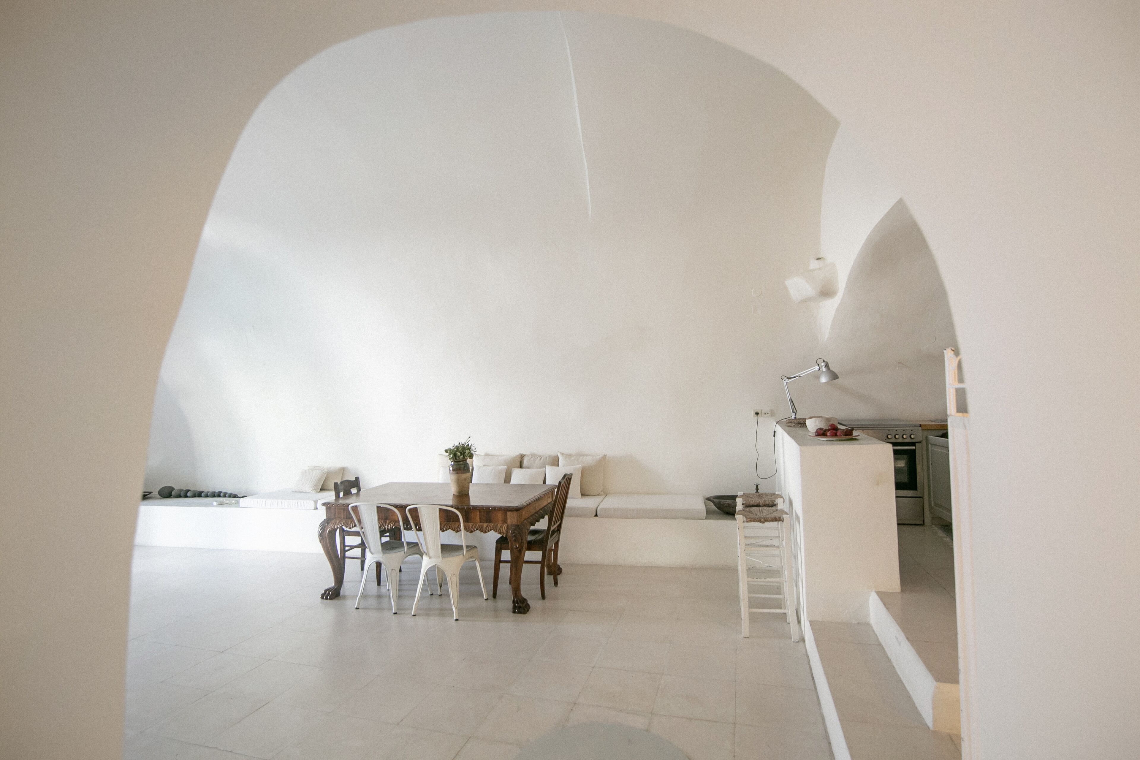 A spacious, modern kitchen with white cabinetry and a dining area featuring a wooden table and white chairs.