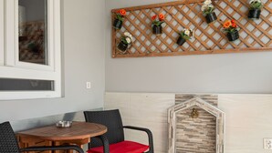 A dining area with a wooden table and chairs, a decorative wall with potted plants, and a stone fireplace. - ★CENTRAL LUXURY MINI SUITE JULIET★JUST RENOVATED (Θεσσαλονίκη)