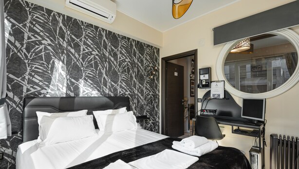 A modern hotel room with a large bed, a round mirror, a desk with a computer, and a view of the city through the window. - ★CENTRAL LUXURY MINI SUITE JULIET★JUST RENOVATED (Θεσσαλονίκη)
