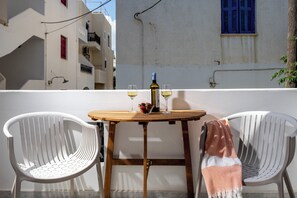 A balcony with a table, two chairs, a bottle of wine, and glasses.