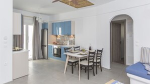 Een moderne keuken met blauwe kastjes, een eettafel met stoelen en een plafondventilator.