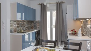 Een moderne keuken met blauwe kastjes, een betegelde spatwand en een eethoek met een tafel gedekt voor twee personen.
