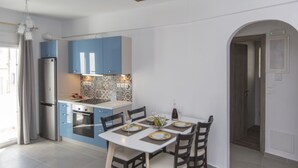 Een moderne keuken met blauwe kastjes, een witte eettafel voor vier personen en een houten plafond.