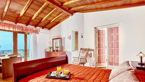 Un dormitorio con una cama grande, cabecera de madera, cómoda, una silla y un balcón con vistas.
