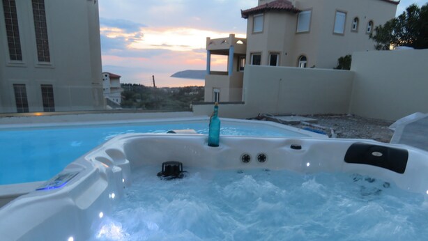 Ein Whirlpool mit Blick auf einen Pool und Gebäude im Hintergrund.