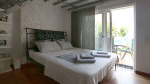 Ein Schlafzimmer mit einem Bett, einem Nachttisch, einem Fenster mit Jalousien und Blick ins Freie.