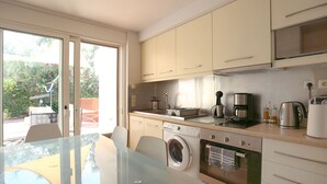 Eine moderne Küche mit einem Glastisch, einer Waschmaschine, einem Backofen und einer Kaffeemaschine.