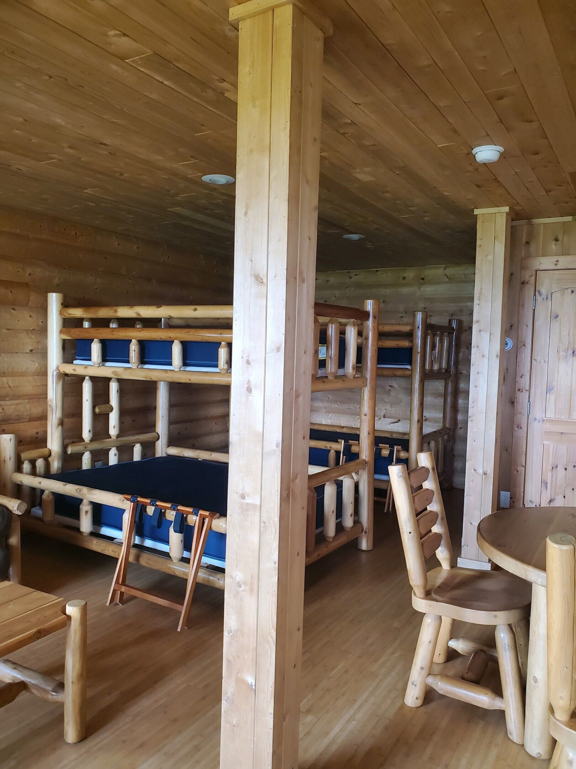 A cabin interior with wooden bunk beds, a dining table, and chairs.
