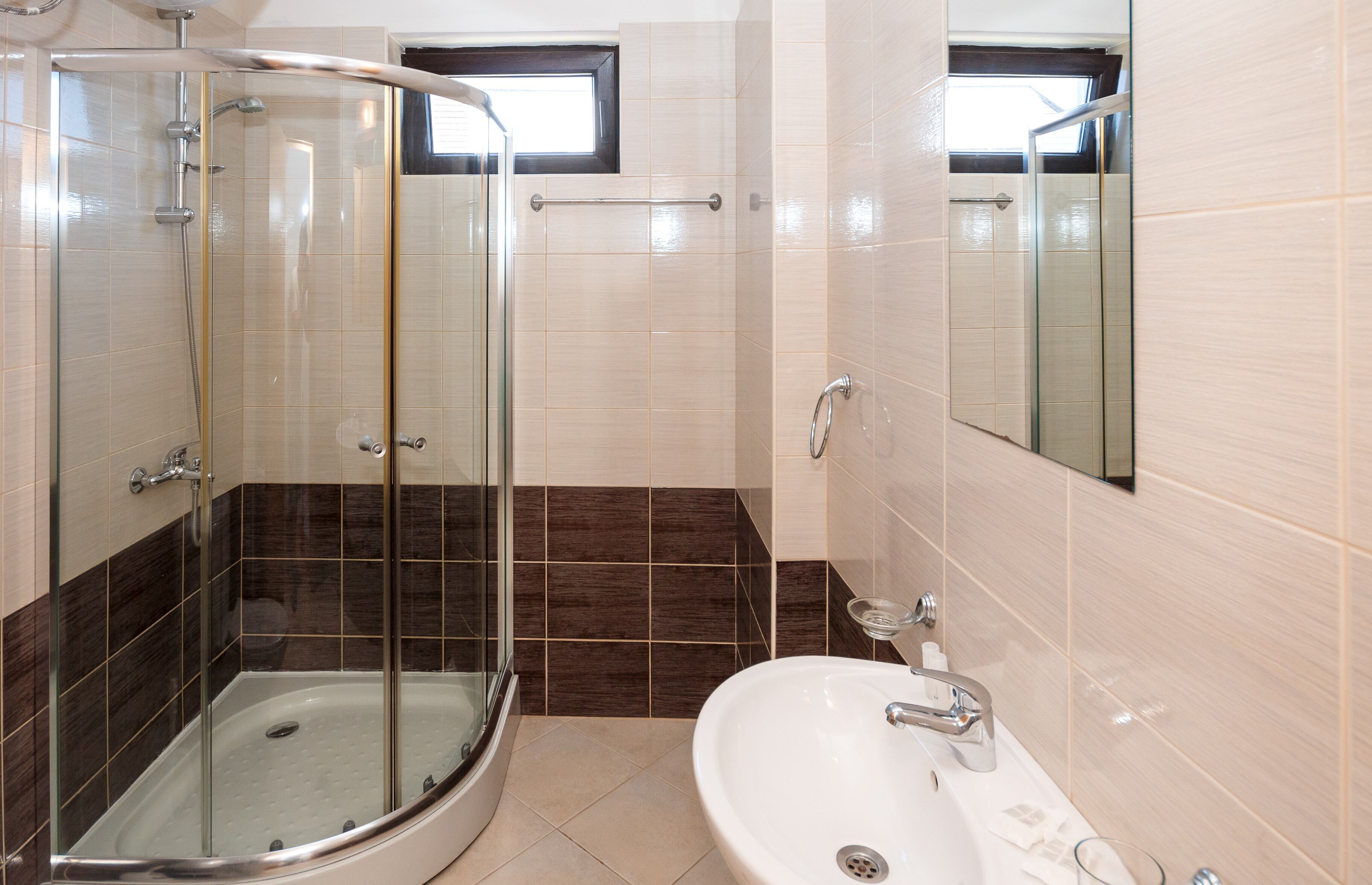 A modern bathroom with a glass-enclosed shower, a white sink, and a mirror.