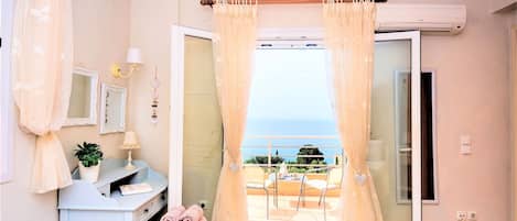 Un dormitorio con cama, escritorio, silla, planta en maceta y vista al mar.