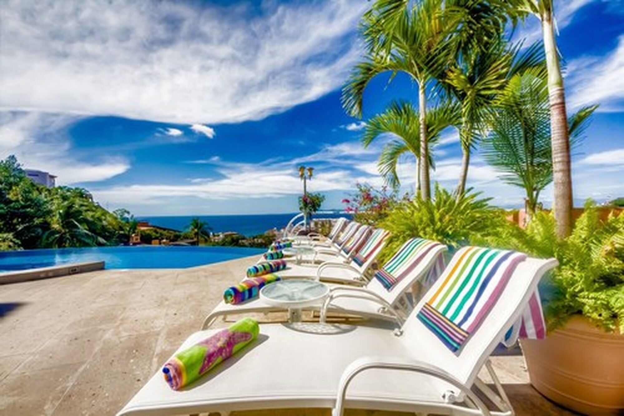 Un espace aménagé au bord de la piscine, avec des chaises longues et une vue sur l’océan.