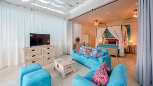 Un salon spacieux avec une grande télévision, un canapé bleu et une table basse en bois.