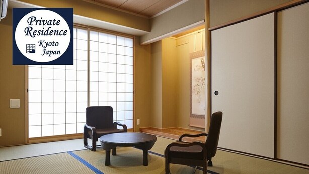 Ein traditioneller japanischer Raum mit Tatami-Bodenbelag, einer Schiebetür und zwei Stühlen.