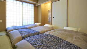 Ein traditionelles japanisches Schlafzimmer mit Tatami-Boden, einem großen Shoji-Fenster und einer Schiebetür.