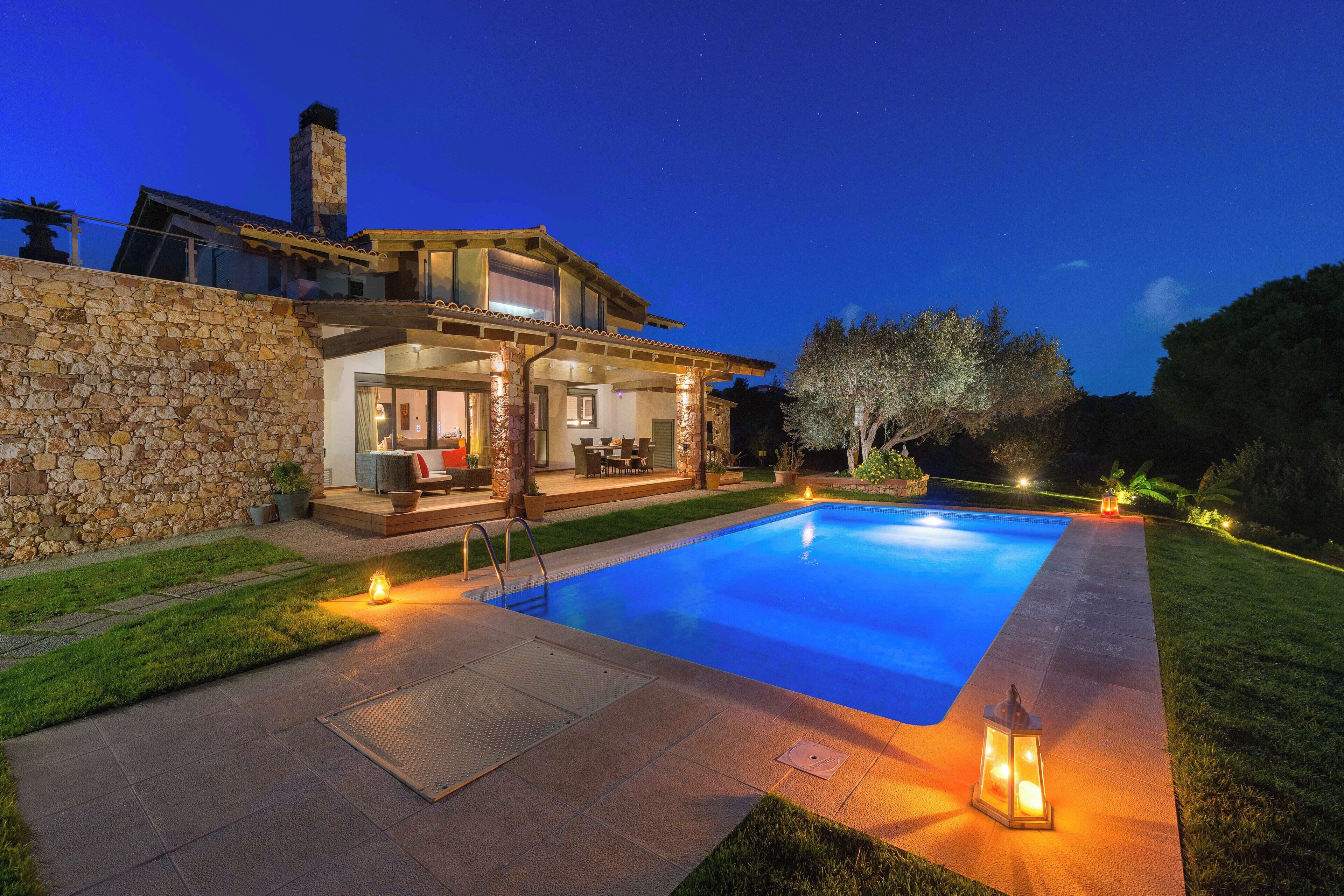 Una casa con piscina, pared de piedra y zona de estar al aire libre.