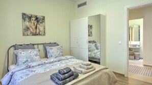 A bedroom with a bed, a wardrobe, a bathroom visible through an open door, and a painting on the wall. - Pasmina Home - Stylish & cozy house, Athens, Plaka (Αθήνα)