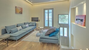 A modern living room with a sectional sofa, a small round table, and a flat-screen TV. - Pasmina Home - Stylish & cozy house, Athens, Plaka (Αθήνα)