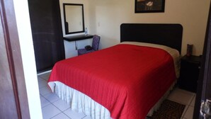 A bedroom with a bed, a desk, a chair, a mirror, and a picture on the wall. - Hotel San Cristobal (Guasave)