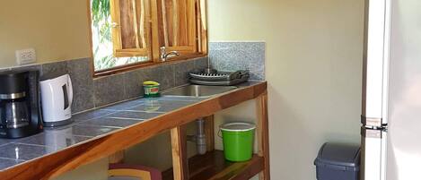 Una cocina compacta con armarios de madera, una encimera, un fregadero, un refrigerador y un suelo de madera con patrón tipo espiga.