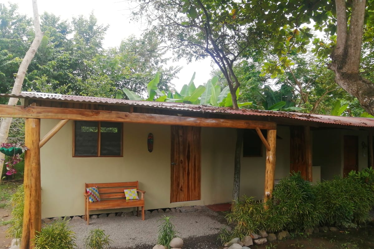 A rustic wooden structure with a bench and a small garden area with rocks and plants.