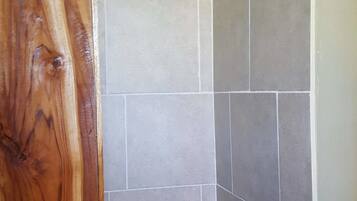 A shower area with tiled walls and a wooden door.