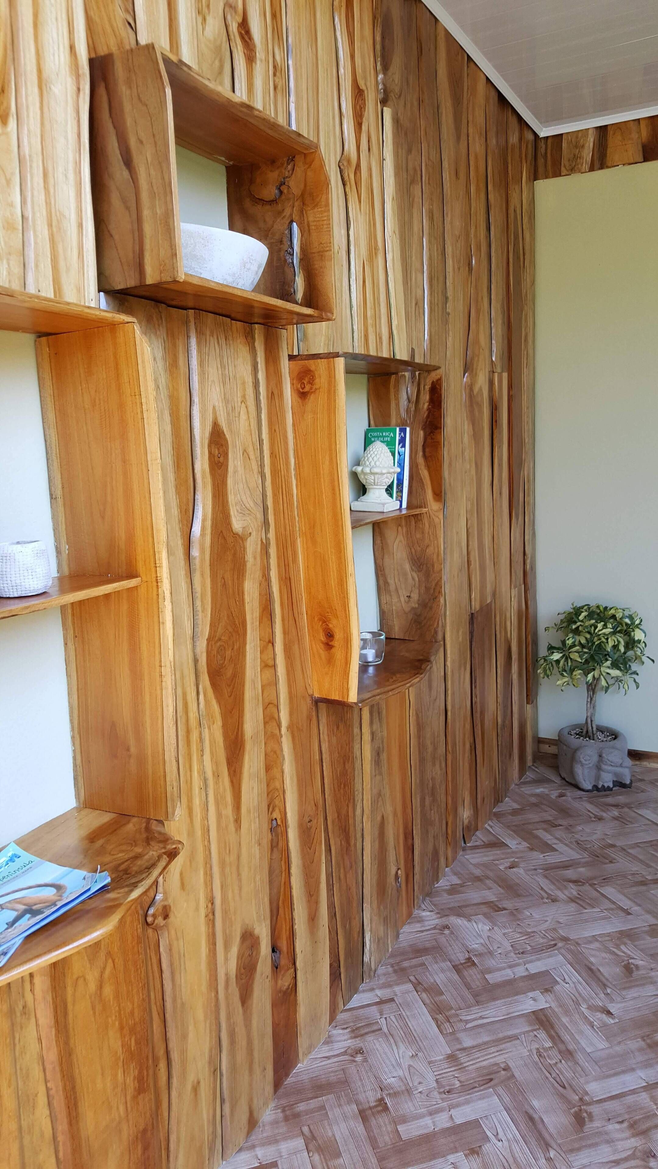 A room with wooden wall shelves, a herringbone-patterned floor, and a potted plant.