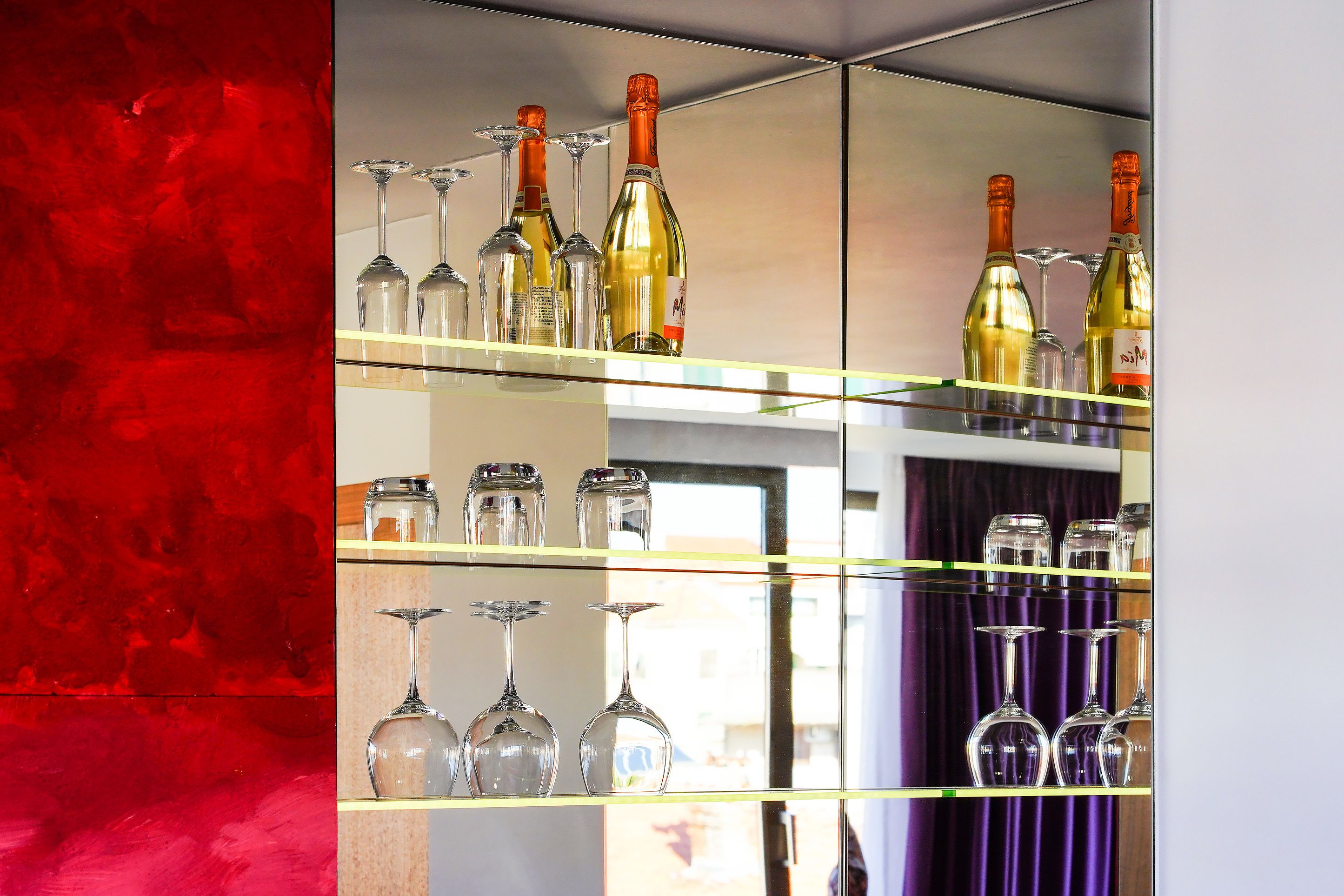 A mirrored wine rack with multiple wine bottles and glasses.