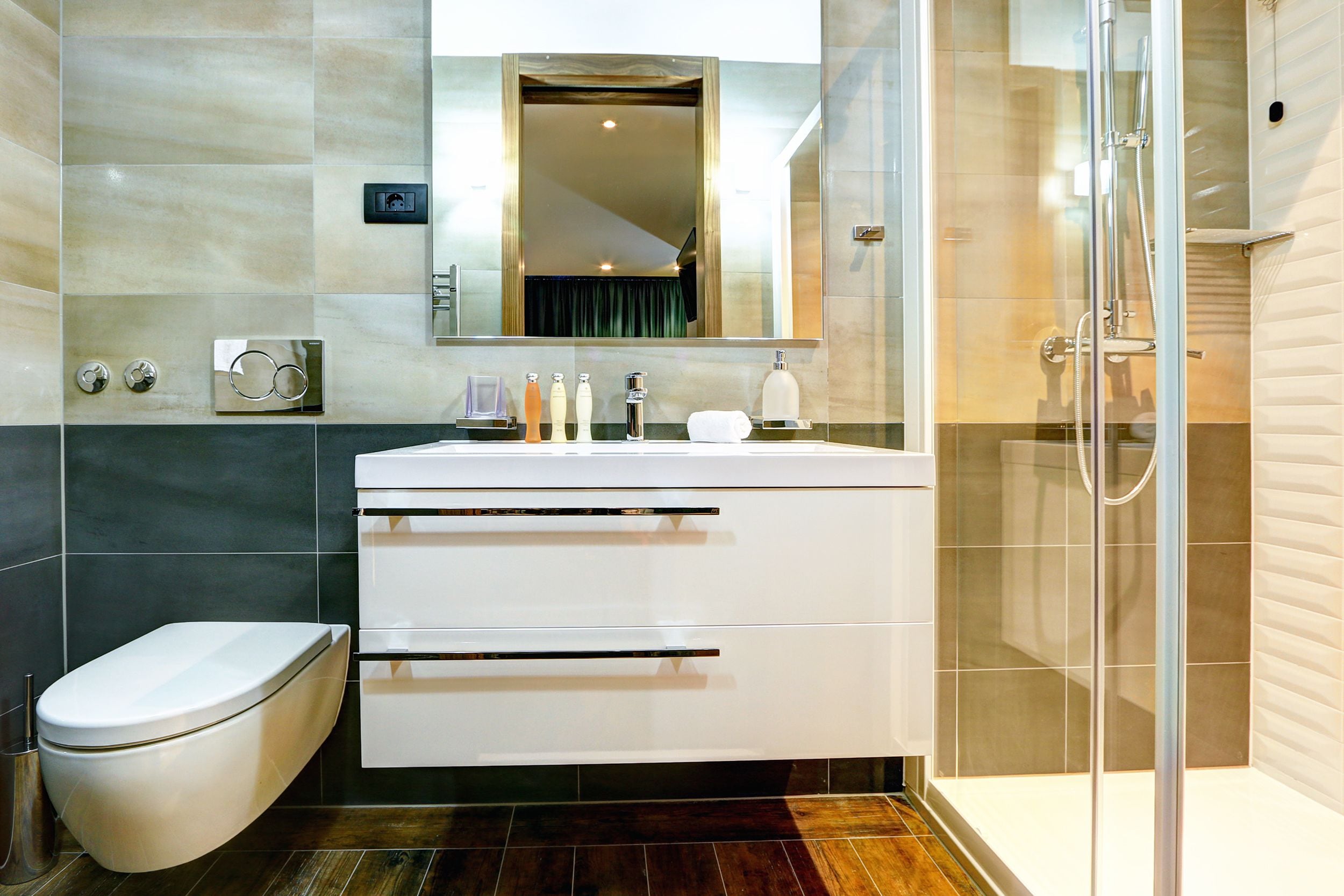 A modern bathroom with a toilet, vanity with a mirror, and a glass-enclosed shower.