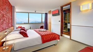 Habitación de hotel moderna con una cama grande, televisión y vistas a la ciudad.