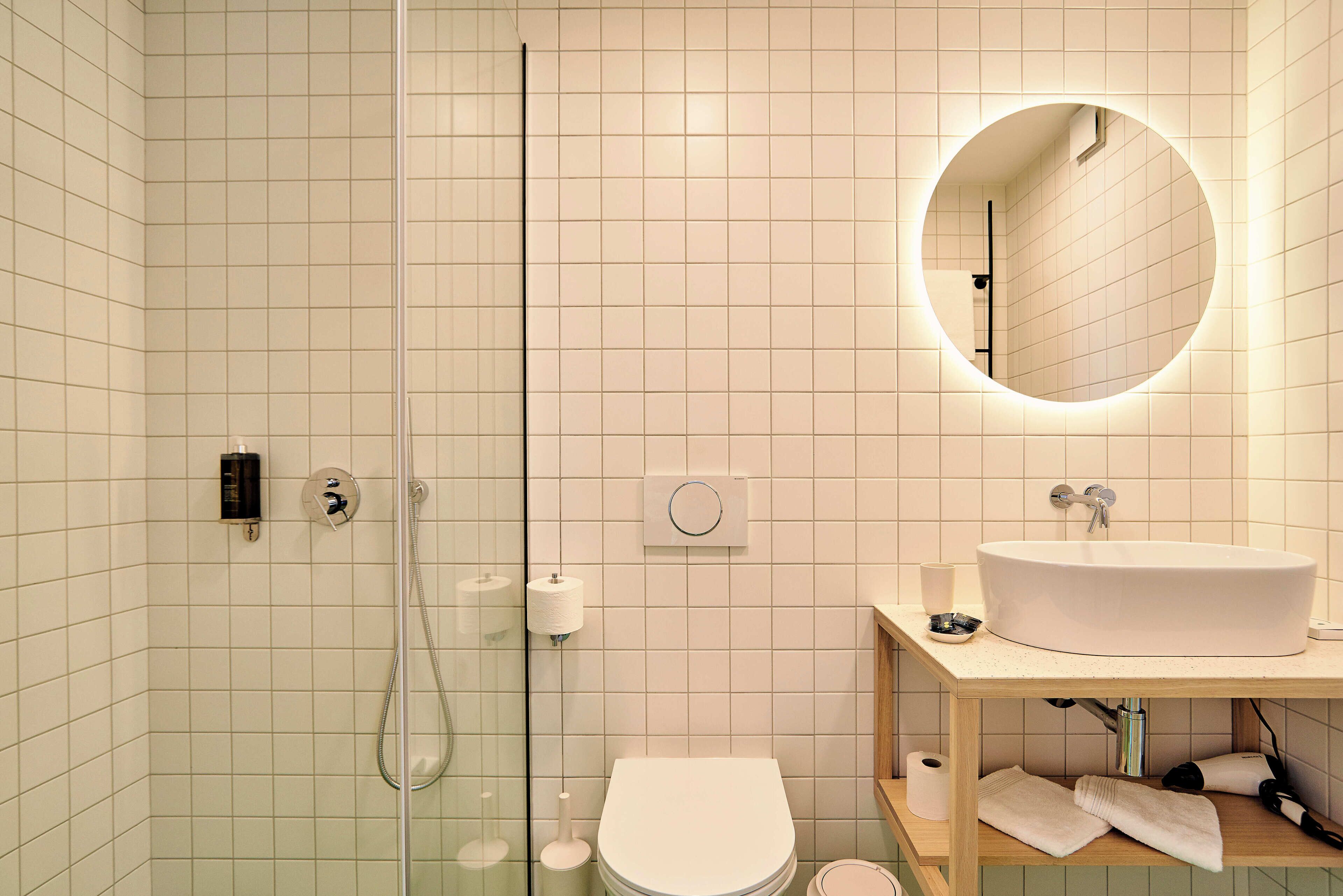 A modern bathroom with a glass shower enclosure, a white toilet, a sink with a mirror, and a towel rack.