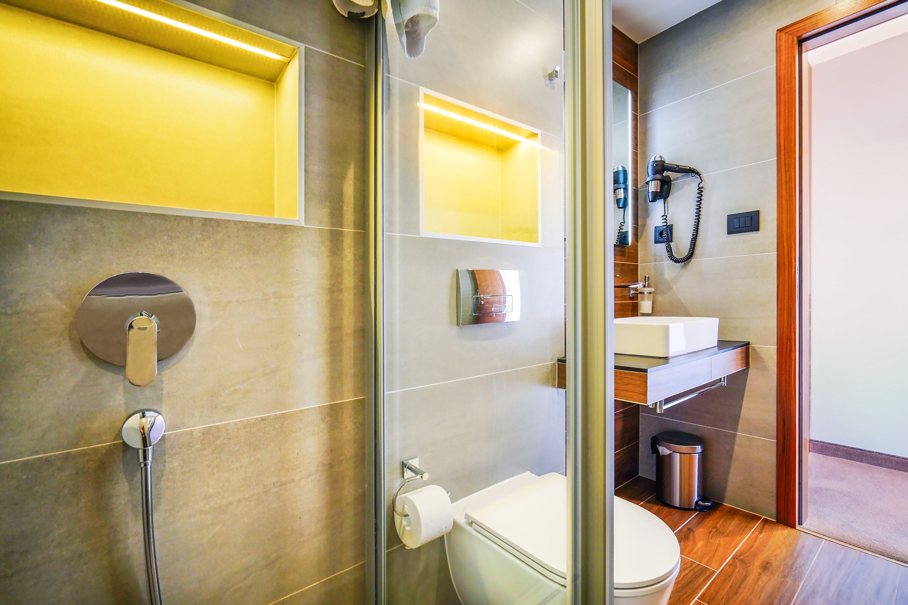 A modern bathroom with a glass shower enclosure, a toilet, and a sink.