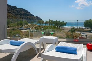 Un balcon avec des fauteuils de relaxation en osier blanc, une table en verre sur laquelle repose un verre à martini et une pomme rouge.