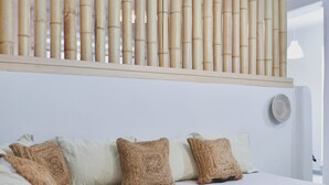 A modern bedroom with a large bed, a headboard with vertical bamboo slats, and a wall-mounted fan. - Apartment in Ag.Anna area,fully equipped,semi-basement & very quiet environment. (Νάξος)