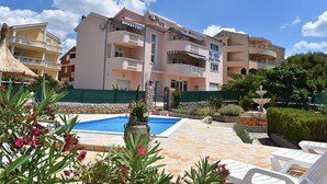 Ein mehrstöckiges Hotel mit Balkonen, einem Swimmingpool und einer Fontäne.