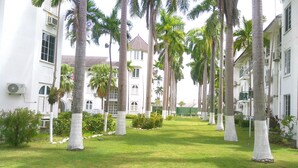 A courtyard with palm trees, a white building with multiple windows, and a green lawn. - Ocho Rios Vacation Resort Property Rent (Ocho Rios)