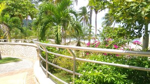 A stone pathway leading to a pool area surrounded by lush greenery and palm trees. - Ocho Rios Vacation Resort Property Rent (Ocho Rios)