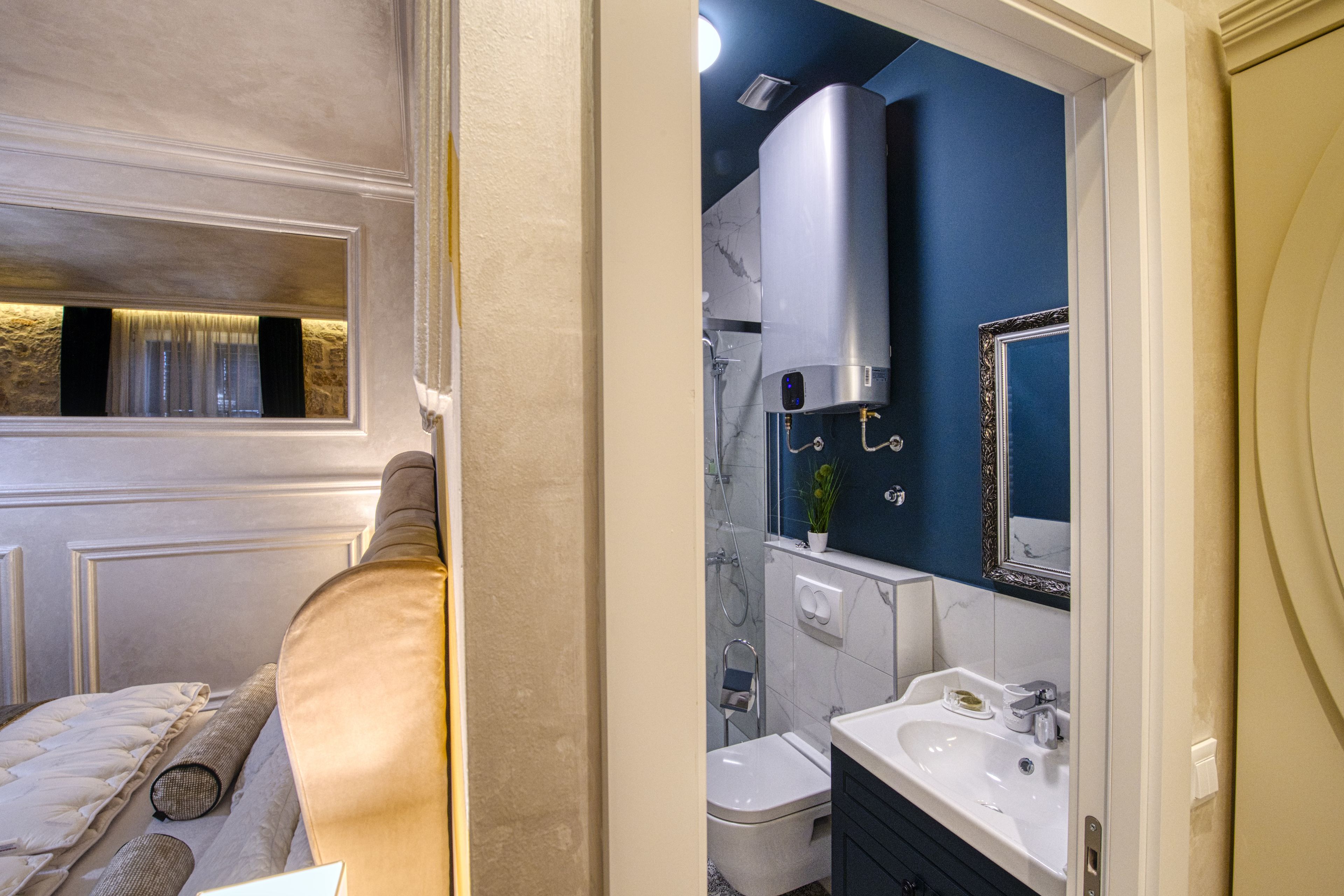 A bathroom with a modern design, featuring a large mirror, a sink, and a toilet.