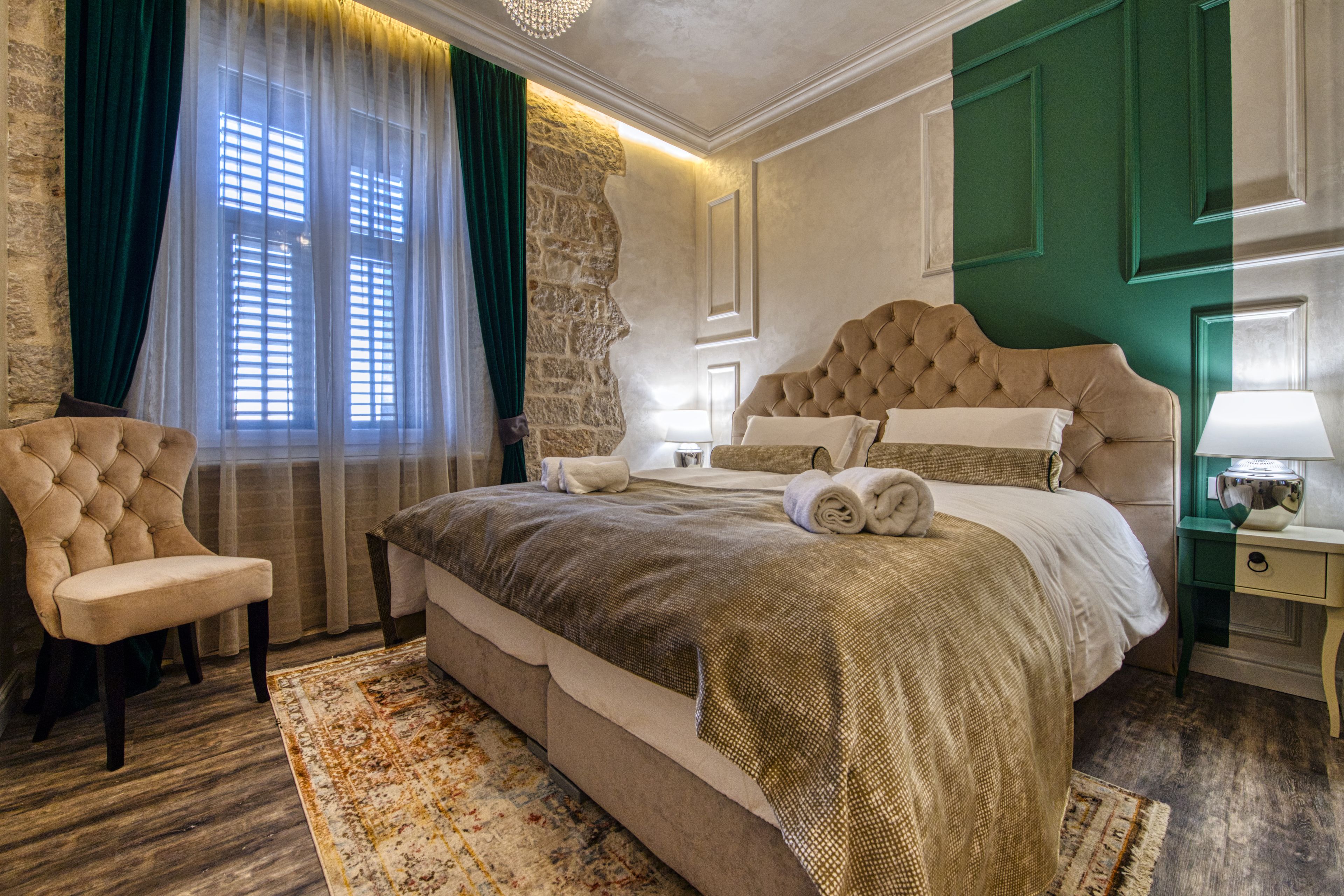 Ein Schlafzimmer mit einem großen Bett, einem Sessel, einem Nachttisch und einer Wand in Grünton.
