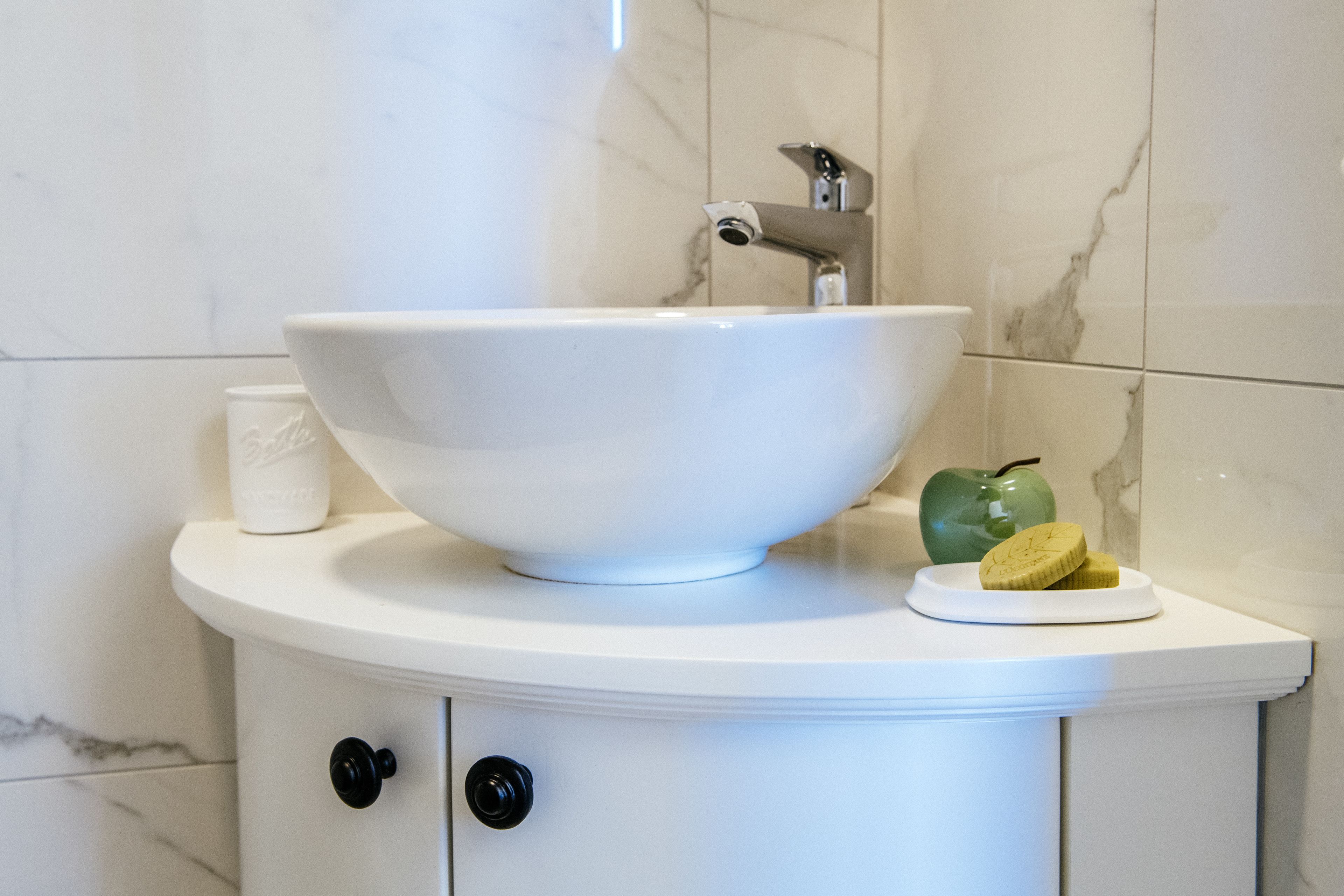 Ein Badezimmer mit einem weißen Waschbecken, einem grünen Apfel und einer Seifenschale.