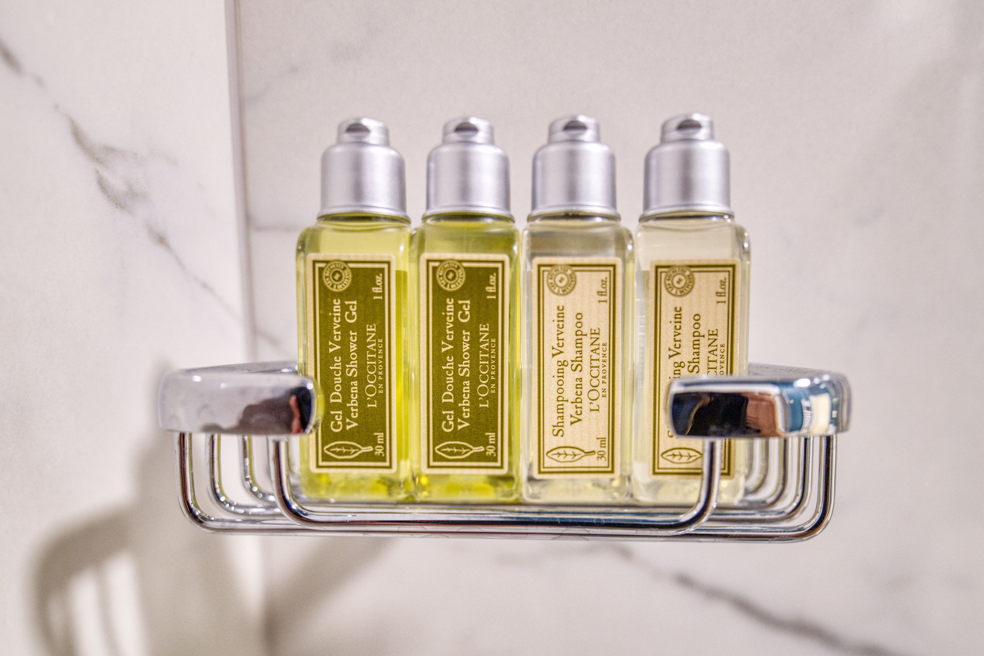 Een badkamerplank met vier flessen L'OCCITANE Verveine douchegel.
