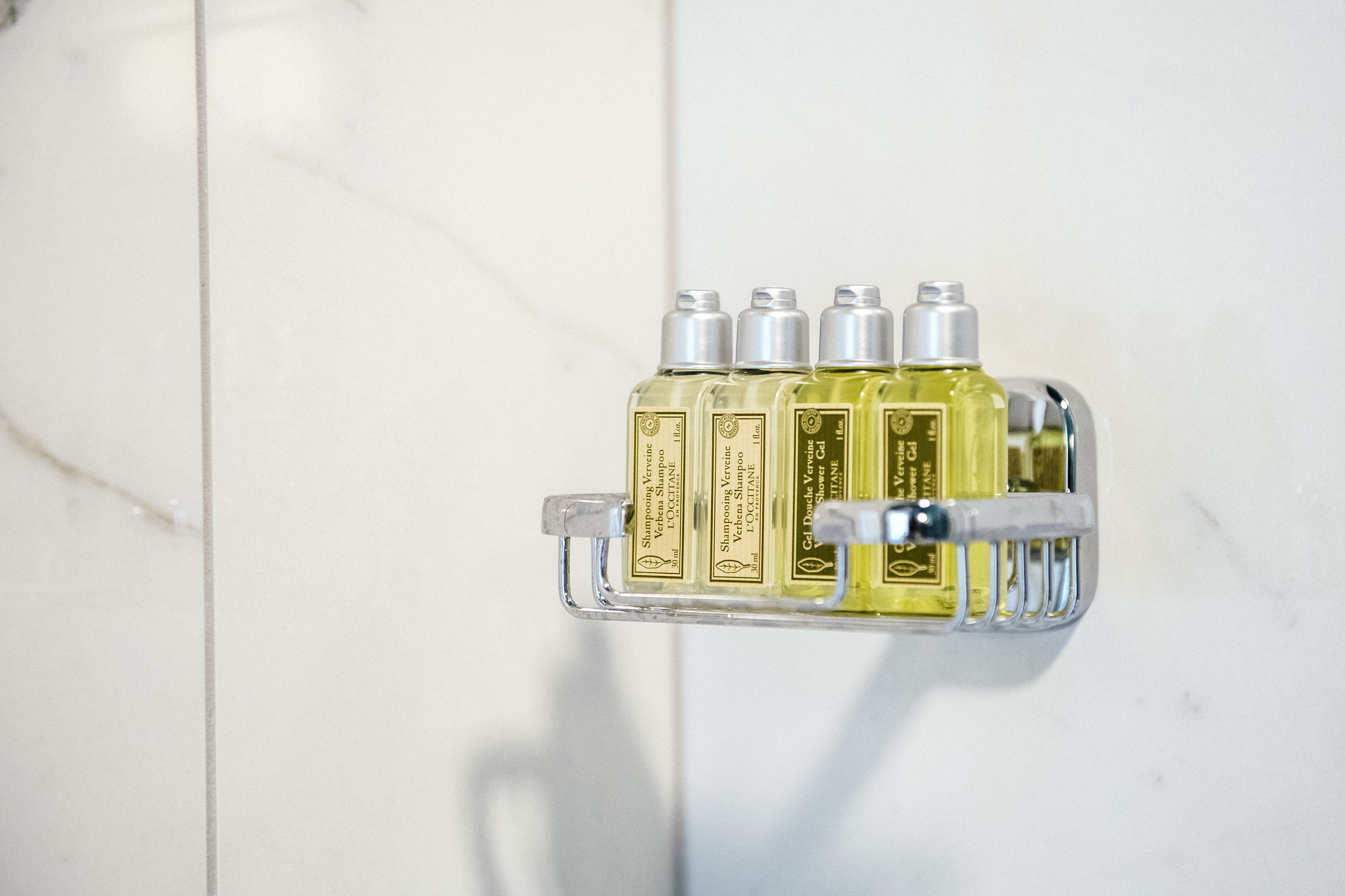 Un estante en el baño con cuatro botellas de champú.