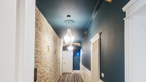 A hallway with a brick wall, wooden flooring, and a chandelier. - Riva Palace - design rooms (Zadar)