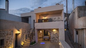 Une cour bordée de murs en pierre, un escalier et un coin repas avec une table et des chaises.