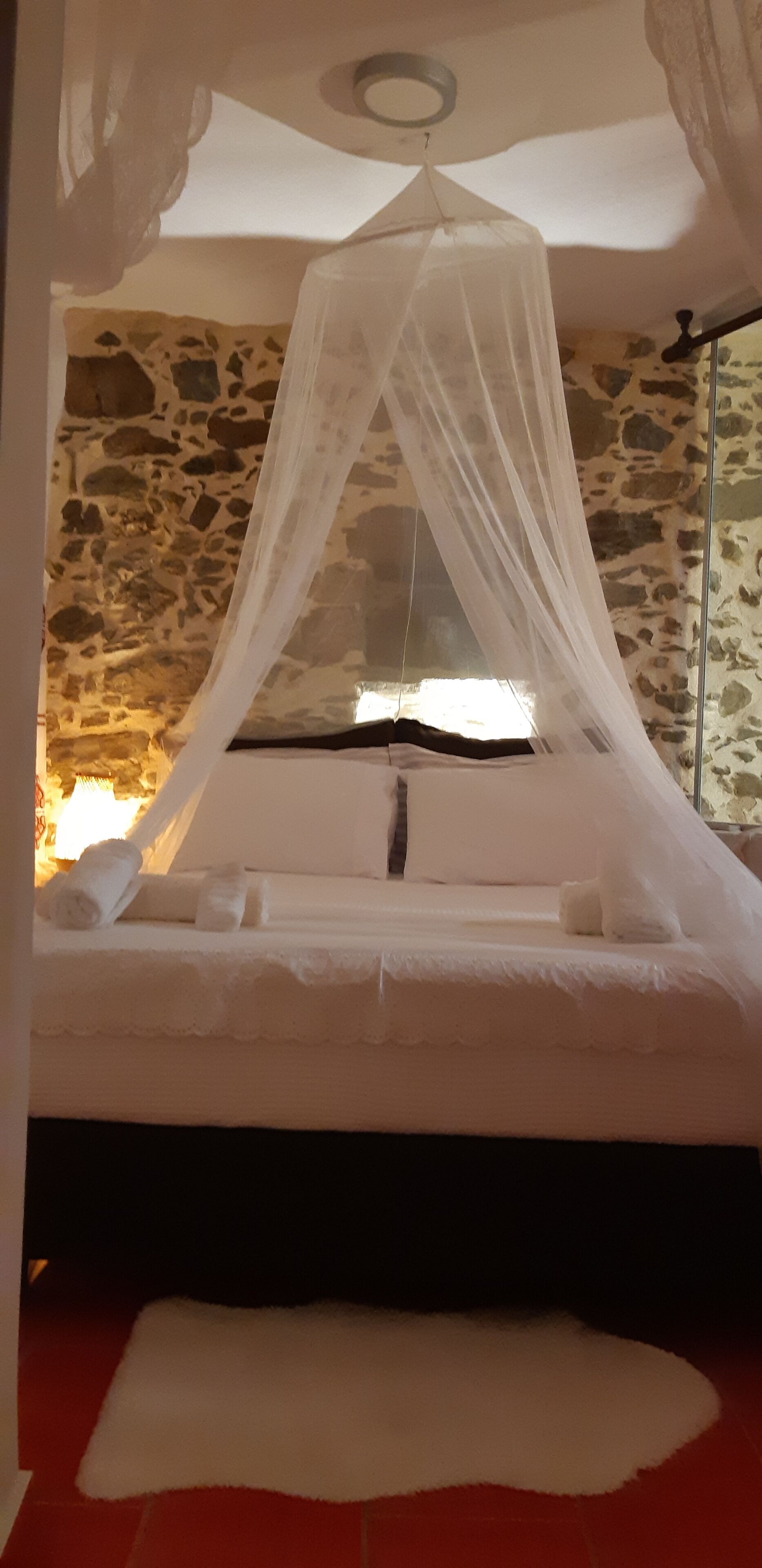 A bed with a canopy in a room with stone walls.