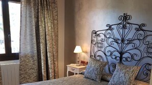 Un dormitorio con una cama grande, una mesita de noche con lámpara y un cabecero decorativo.