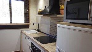 Una cocina equipada con estufa integrada, un lavamanos y un microondas.