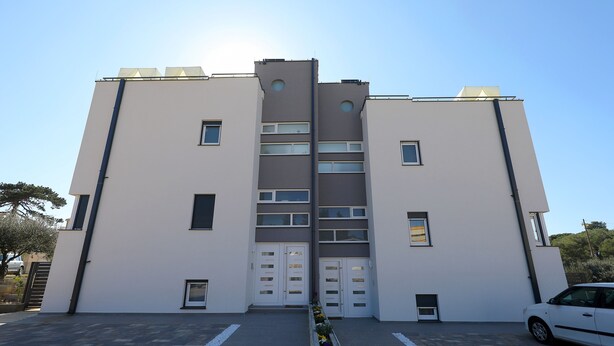 A modern building with a symmetrical facade, two main entrances, and a parking area with a white car. - Villa Harmony (Zadar)
